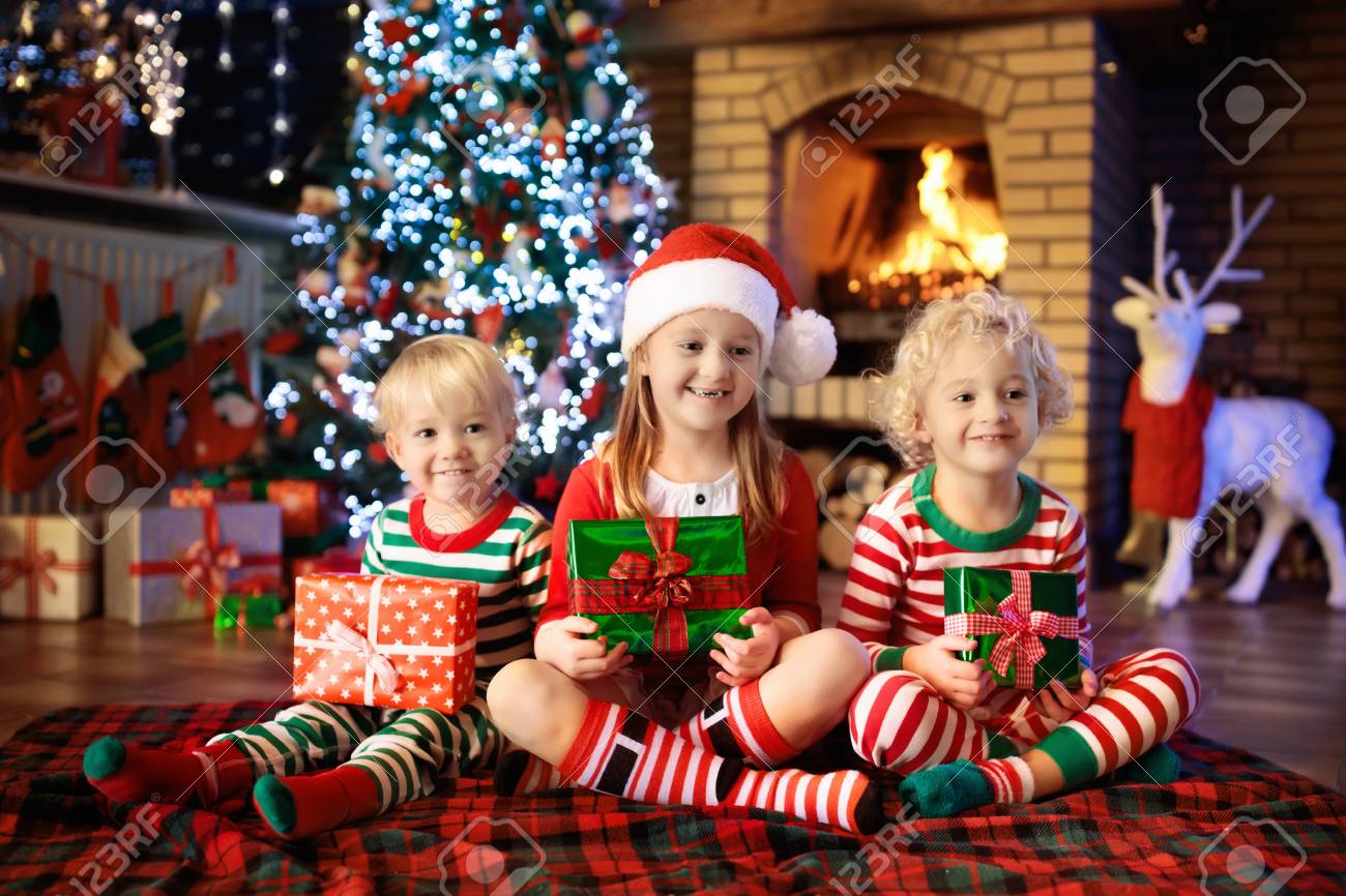 Child at Christmas tree. Kids at fireplace on Xmas
