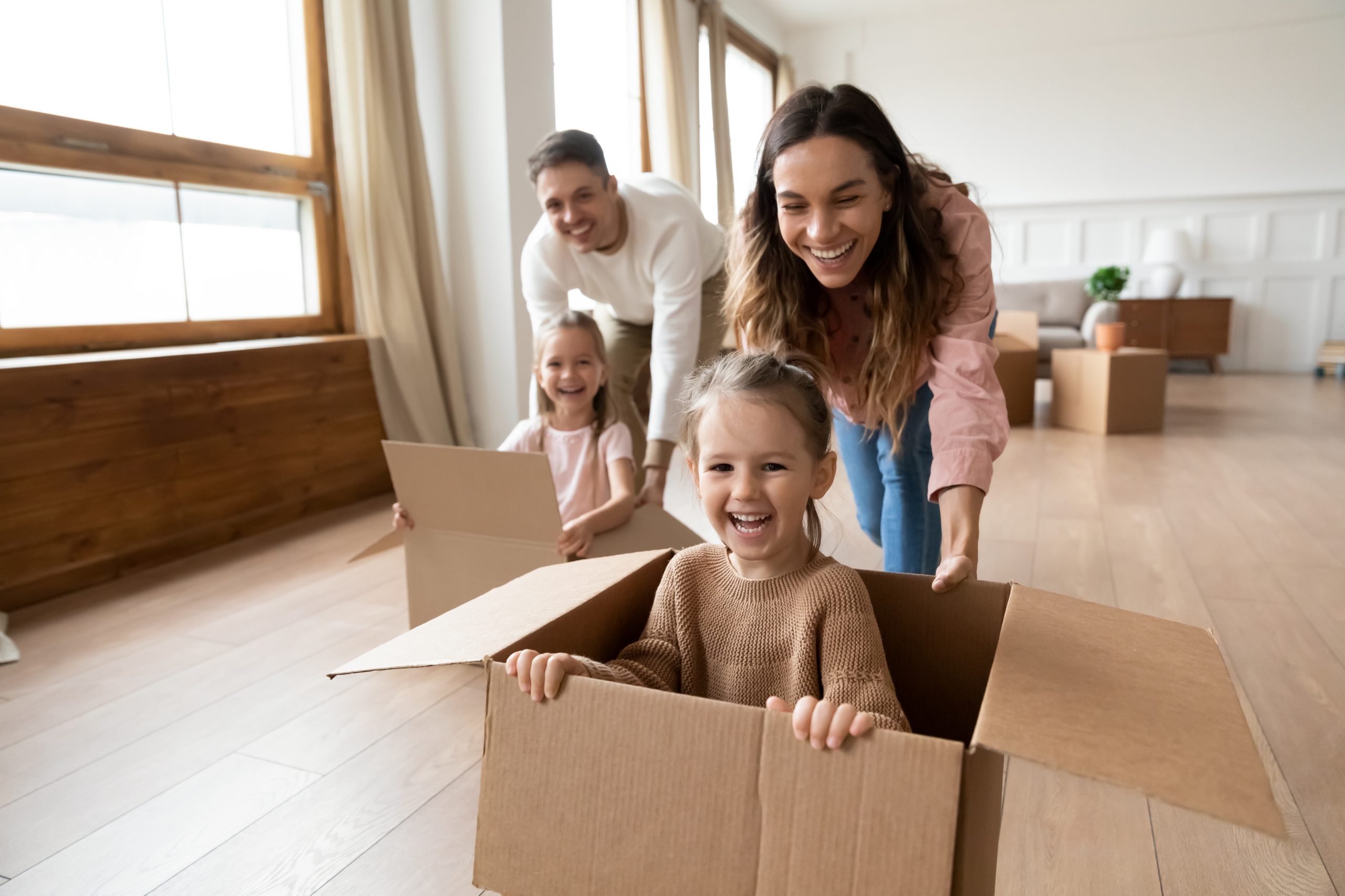 happy family pushing child in box in home